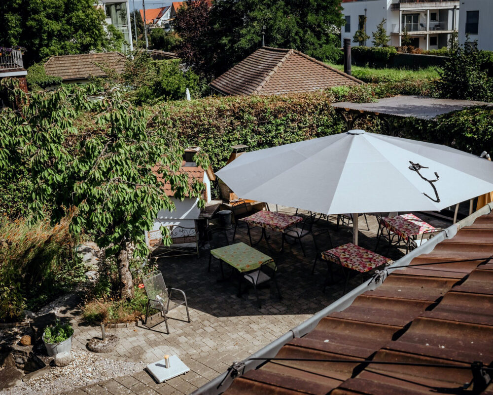 Blick in den Garten mit einem grossen Sonnenschirm